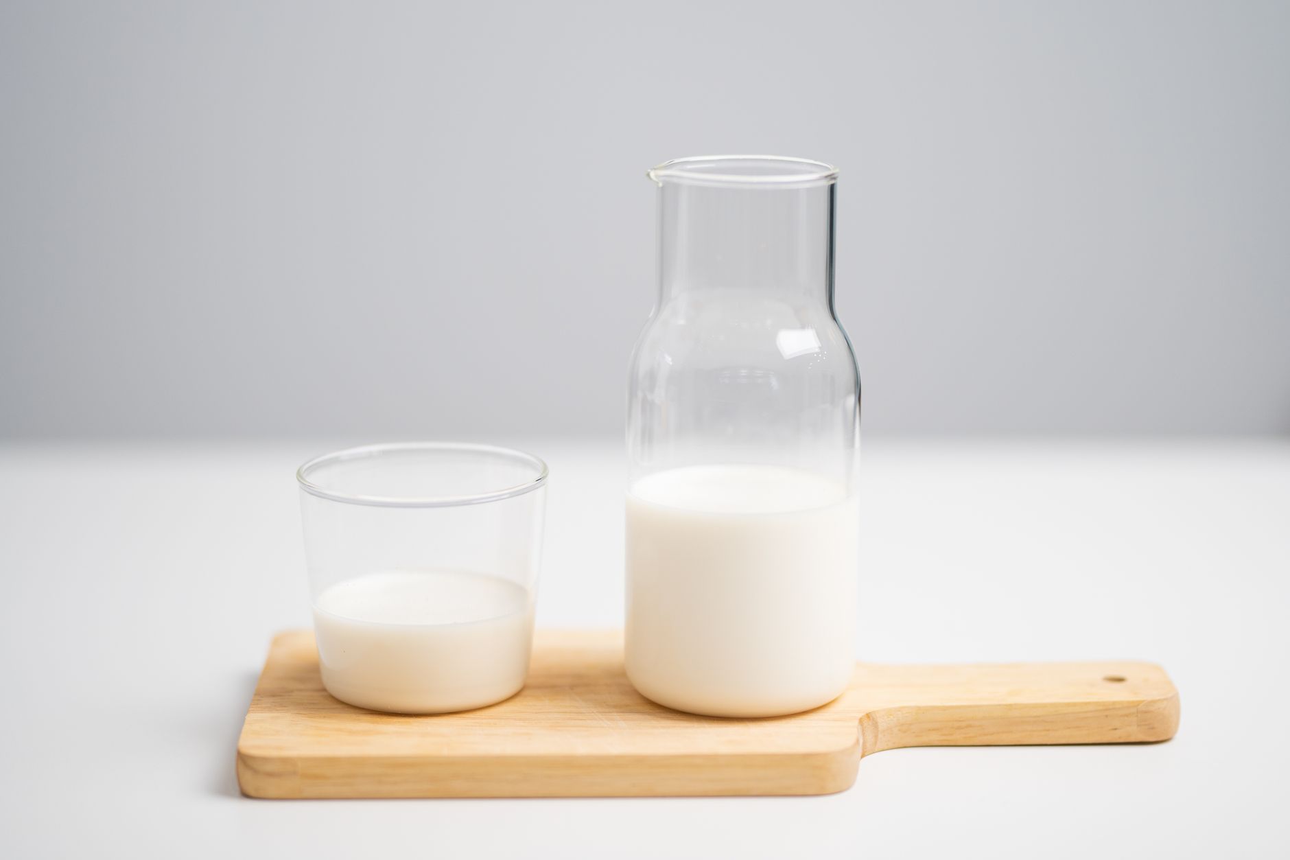 木のボードに置かれた白い飲み物のピッチャーとグラス