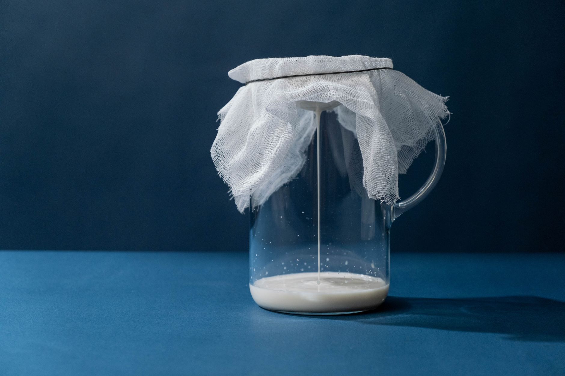 ガラスの容器に白い飲み物を注いでいる様子