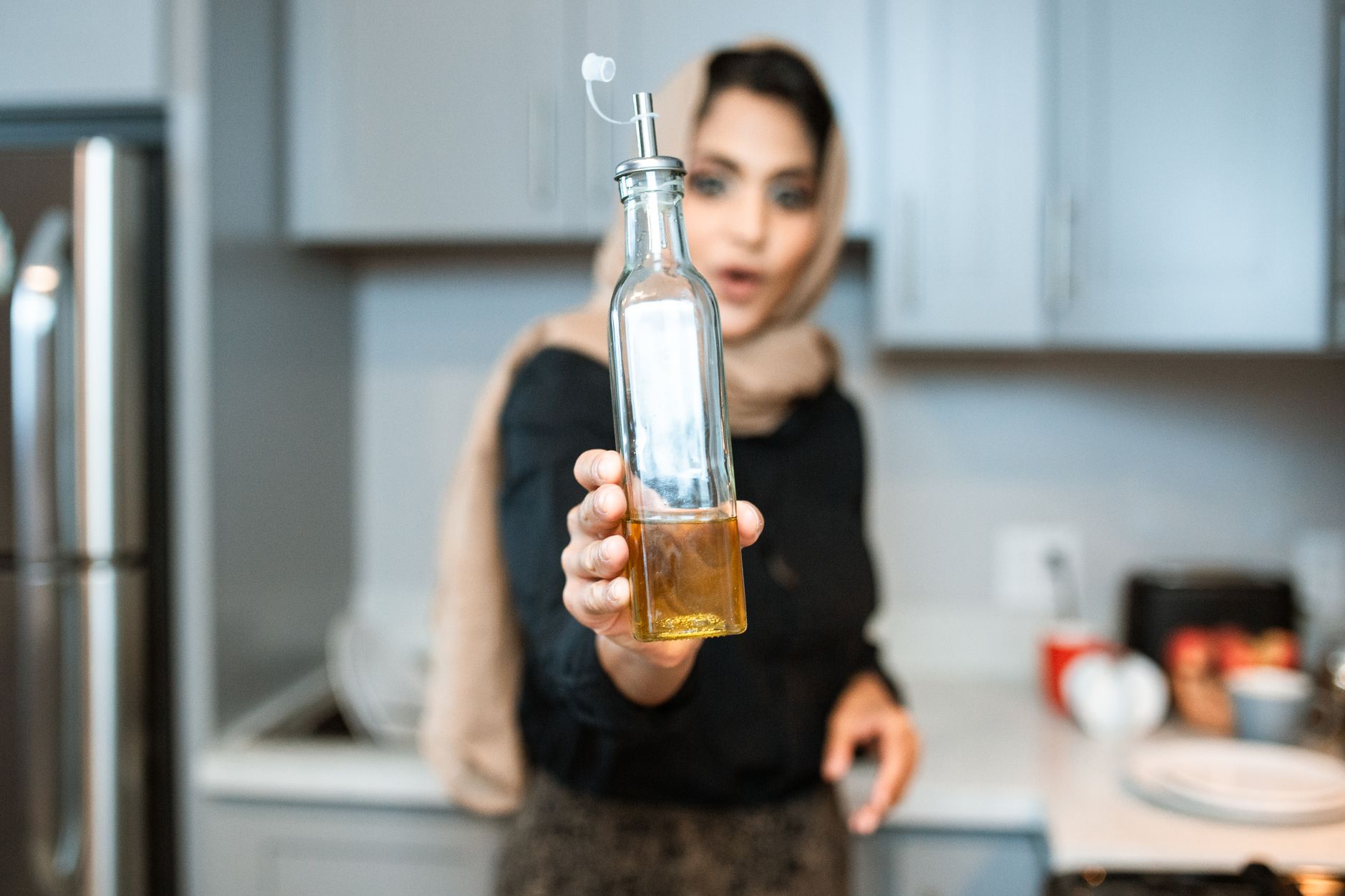 キッチンで食用油のボトルを手に持つ様子